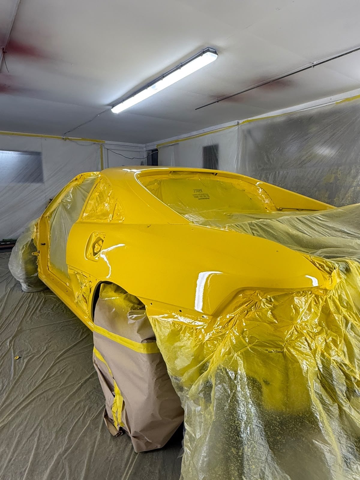 After — Panels prepared and masked ahead of a full respray, refinished in a bright yellow with a fresh, even gloss.